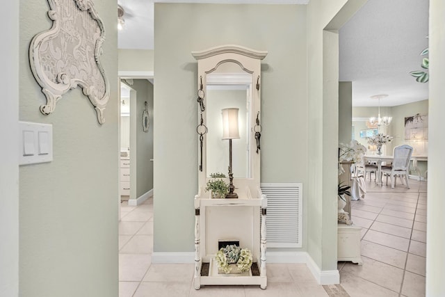 hallway with a chandelier and light tile patterned floors