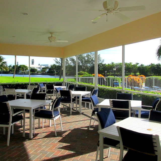 view of patio with outdoor dining space, a water view, and a ceiling fan