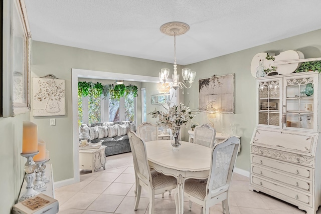 dining space featuring light tile patterned floors, a textured ceiling, baseboards, and an inviting chandelier