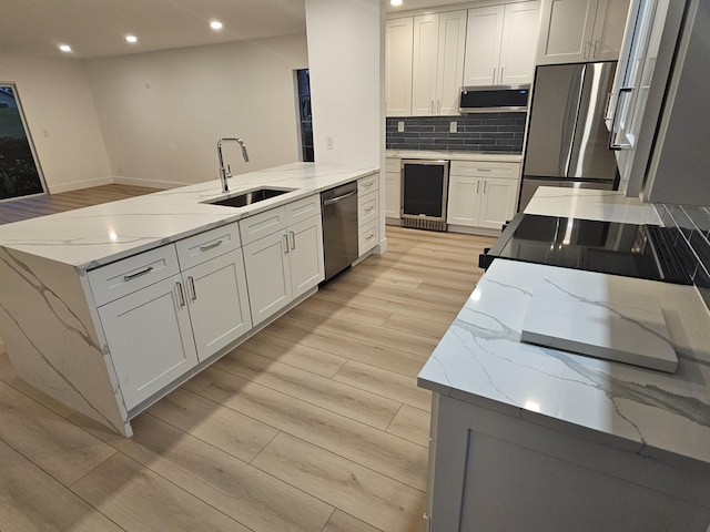 kitchen with appliances with stainless steel finishes, sink, white cabinets, and light stone counters