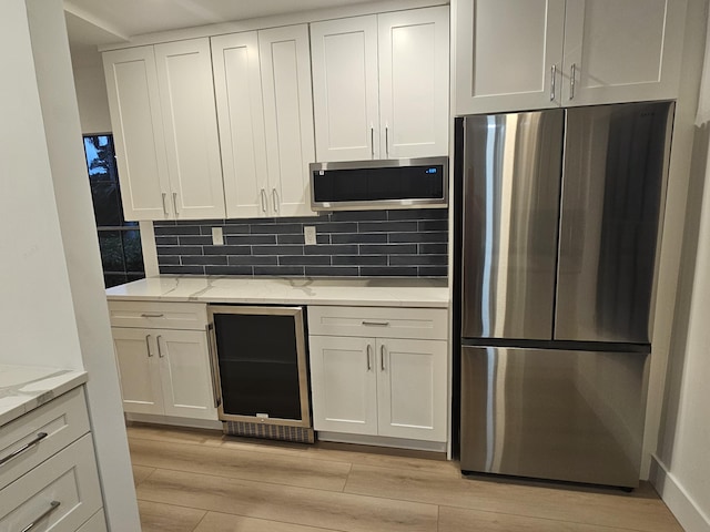 kitchen featuring wine cooler, light stone counters, white cabinets, and appliances with stainless steel finishes