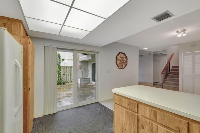 kitchen featuring white fridge and dark colored carpet