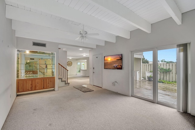 unfurnished room featuring ceiling fan, light colored carpet, beam ceiling, and a wealth of natural light