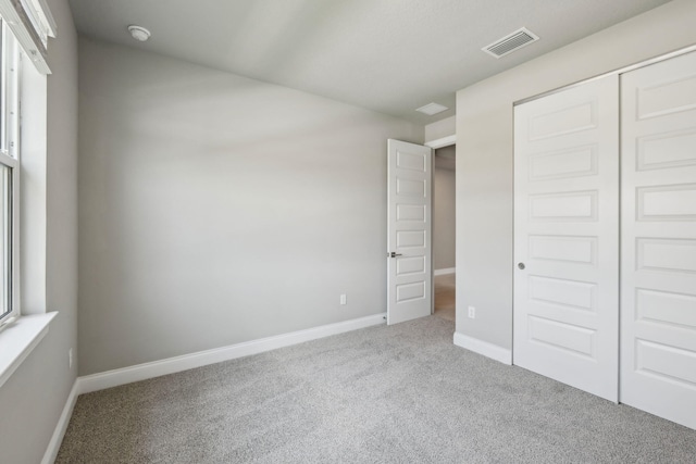 unfurnished bedroom featuring a closet, visible vents, carpet, and baseboards