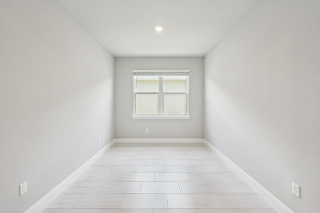 spare room with recessed lighting and baseboards