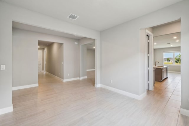 unfurnished room with recessed lighting, light wood-style floors, a sink, baseboards, and visible vents