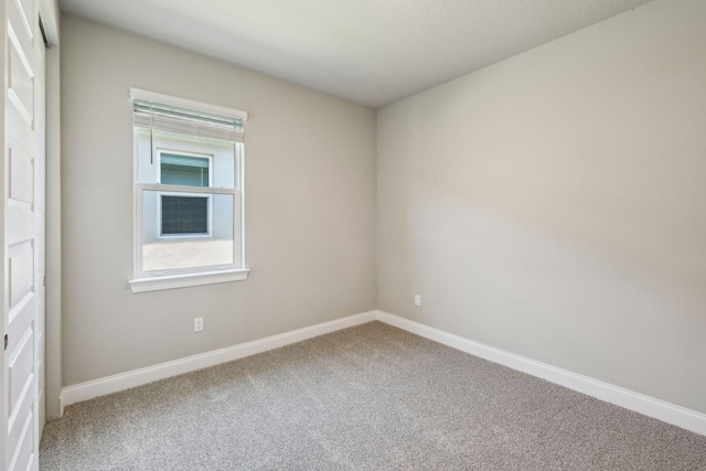 spare room featuring carpet and baseboards