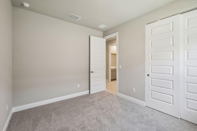 unfurnished bedroom featuring baseboards, visible vents, light carpet, and a closet
