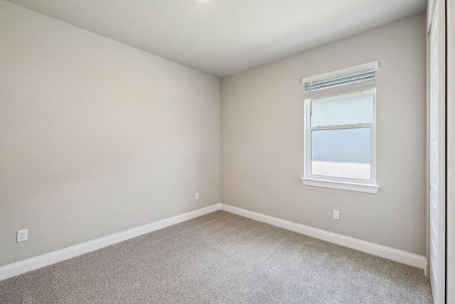 carpeted empty room featuring baseboards
