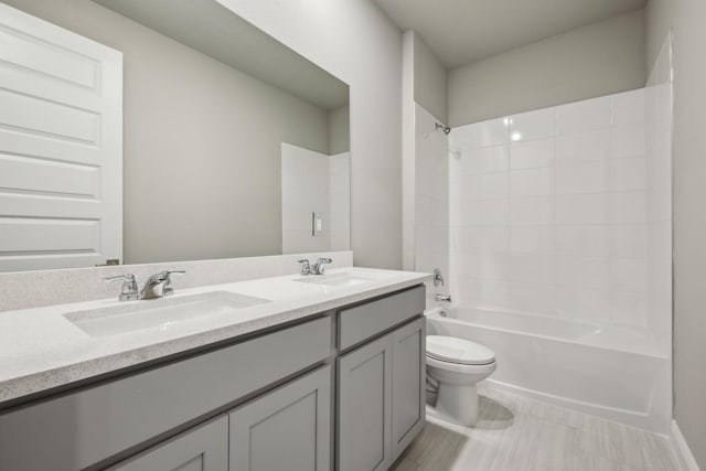 bathroom featuring toilet, double vanity, a sink, and shower / tub combination