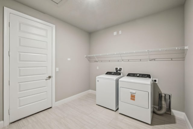 washroom featuring separate washer and dryer, laundry area, and baseboards