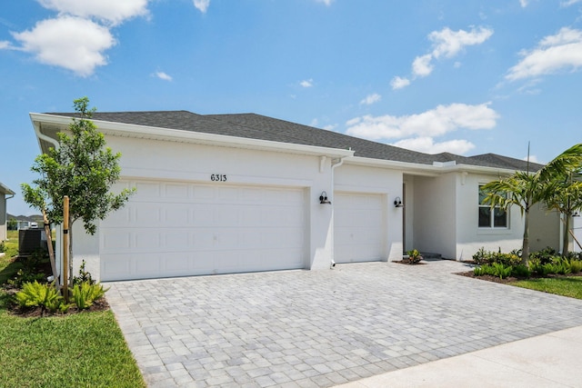 ranch-style house featuring stucco siding, decorative driveway, and an attached garage