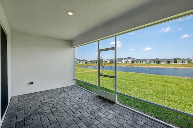 unfurnished sunroom with a residential view and a water view