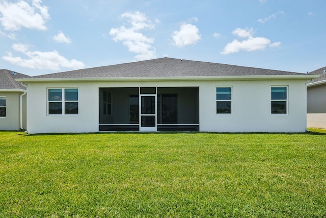 rear view of property with stucco siding, a yard, and a sunroom