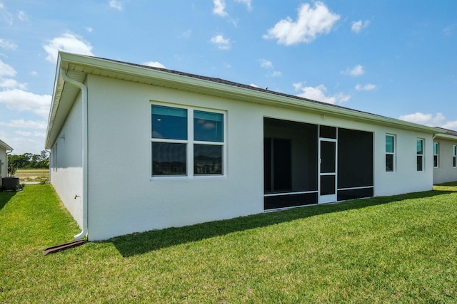 back of house with stucco siding, a yard, and central air condition unit