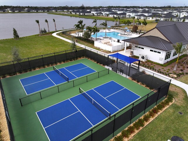 view of sport court featuring a residential view, a fenced in pool, a water view, a lawn, and fence