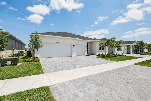 ranch-style house featuring stucco siding, decorative driveway, a front lawn, and an attached garage