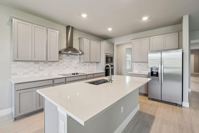 kitchen with a sink, gray cabinetry, stainless steel appliances, wall chimney exhaust hood, and backsplash