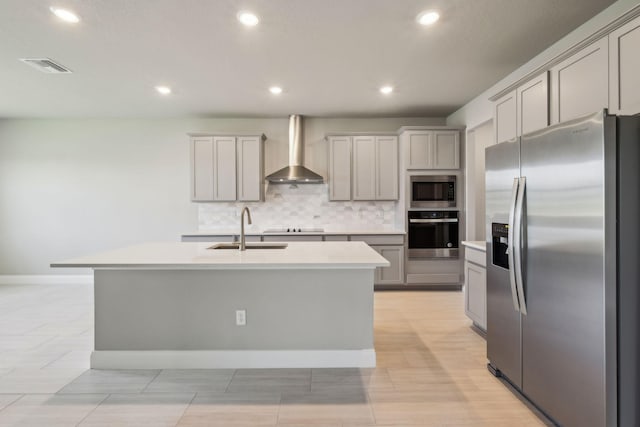 kitchen featuring a sink, decorative backsplash, wall chimney exhaust hood, visible vents, and appliances with stainless steel finishes