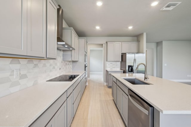 kitchen featuring decorative backsplash, a sink, appliances with stainless steel finishes, light countertops, and wall chimney exhaust hood