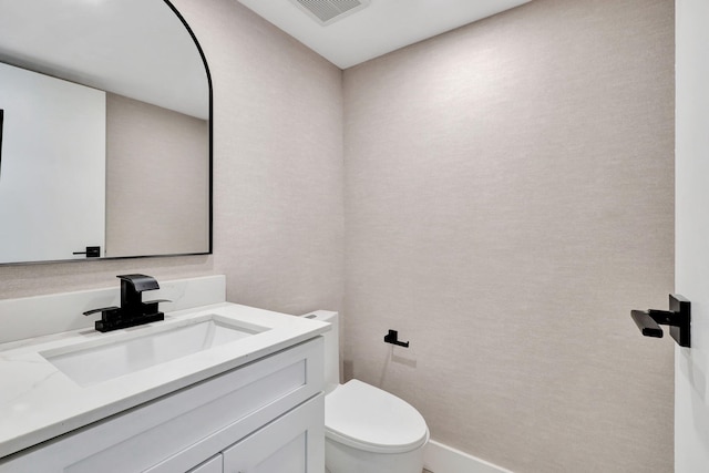 half bath featuring visible vents, vanity, and toilet