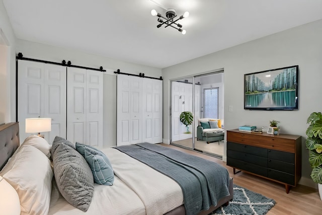 bedroom featuring multiple closets, light wood-type flooring, and a barn door