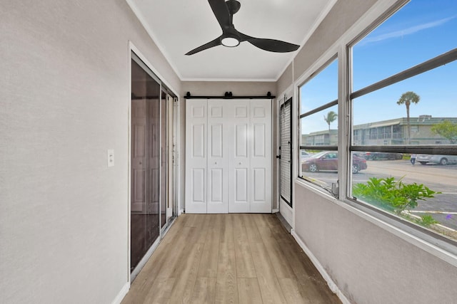 hallway featuring crown molding, a barn door, and light hardwood / wood-style floors