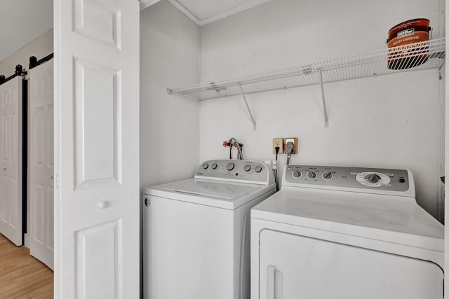 washroom with light hardwood / wood-style floors, washer and dryer, and a barn door