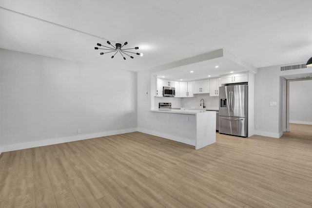 kitchen featuring stainless steel appliances, visible vents, white cabinetry, light countertops, and light wood finished floors