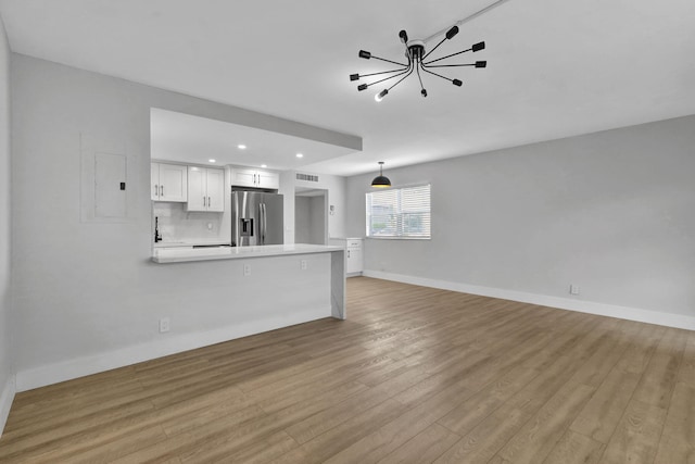 unfurnished living room with visible vents, baseboards, wood finished floors, an inviting chandelier, and recessed lighting