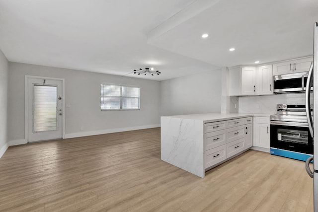 kitchen with stainless steel appliances, a peninsula, white cabinetry, open floor plan, and light wood finished floors