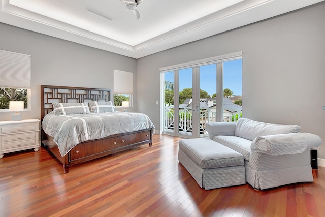 bedroom featuring hardwood / wood-style floors, access to exterior, ceiling fan, a raised ceiling, and french doors