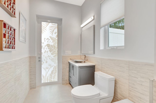 bathroom featuring vanity, toilet, tile patterned flooring, and tile walls