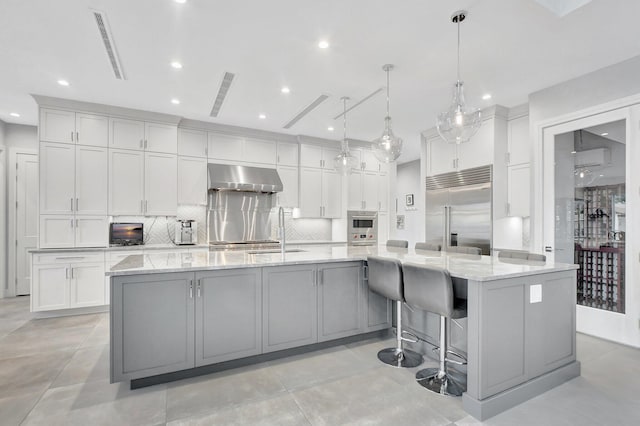 kitchen featuring stainless steel appliances, a spacious island, decorative light fixtures, and range hood