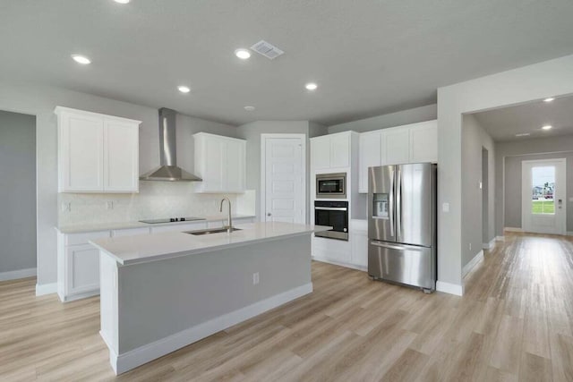 kitchen featuring wall chimney range hood, black appliances, sink, and white cabinets