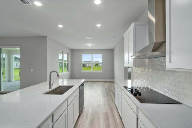 kitchen with white cabinetry, sink, black electric stovetop, light stone countertops, and wall chimney exhaust hood