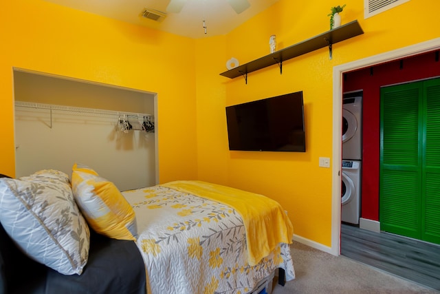 carpeted bedroom featuring stacked washer / drying machine