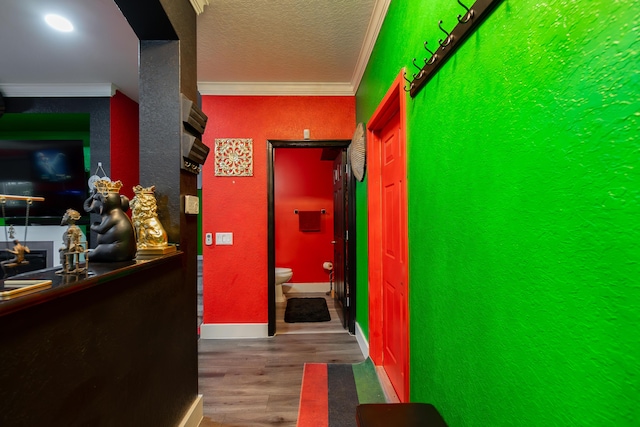 hall with crown molding, wood-type flooring, and a textured ceiling