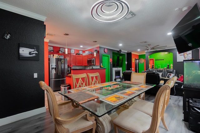 dining space featuring crown molding, wood-type flooring, a textured ceiling, and ceiling fan