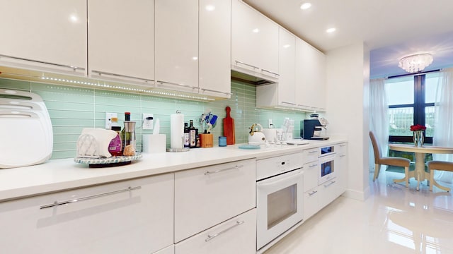 kitchen with decorative backsplash, oven, white cabinets, and premium range hood