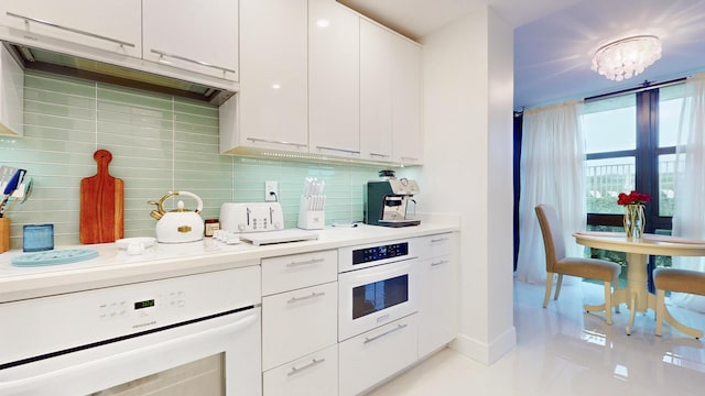 kitchen with light tile patterned flooring, white cabinetry, range, white oven, and backsplash