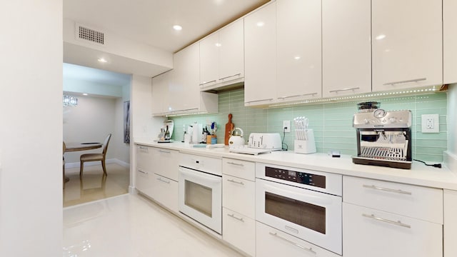 kitchen with white cabinetry, oven, decorative backsplash, and light tile patterned floors