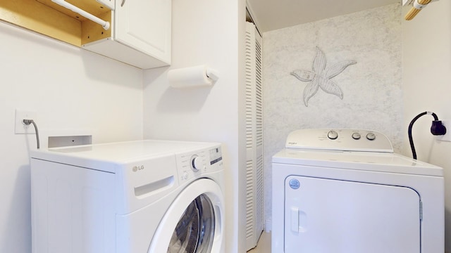 laundry room with washing machine and dryer and cabinets