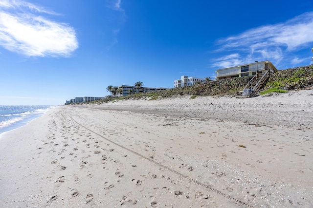 view of property's community featuring a water view and a beach view