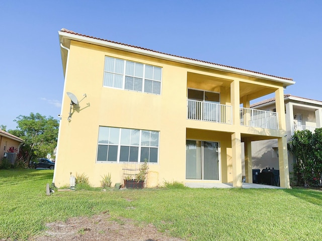 back of house featuring a balcony and a lawn