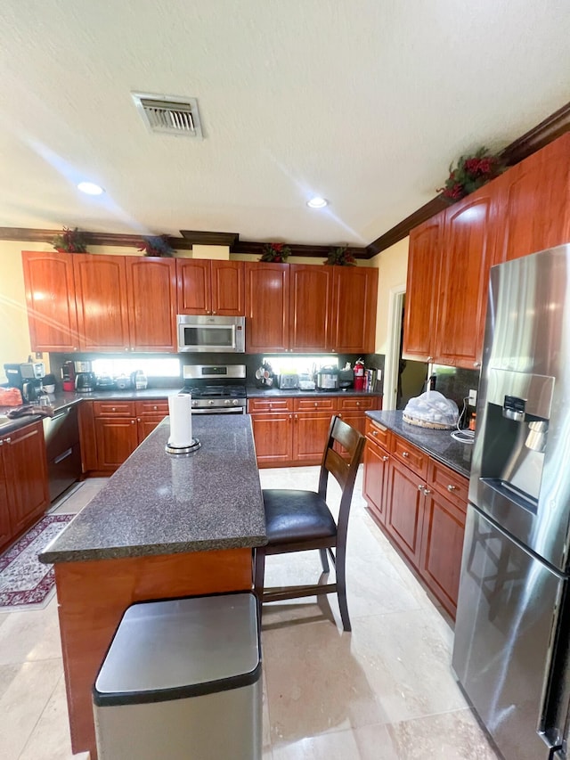 kitchen with a kitchen island, appliances with stainless steel finishes, backsplash, dark stone counters, and ornamental molding