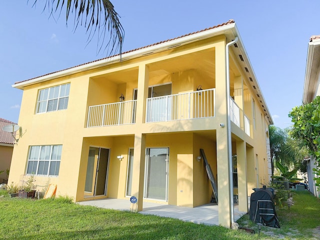 back of property with a balcony, a yard, and a patio area