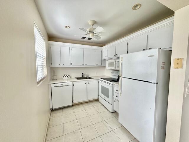 kitchen with light tile patterned flooring, sink, white cabinetry, ceiling fan, and white appliances