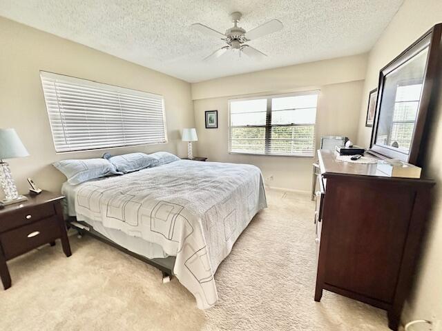 bedroom featuring multiple windows, light carpet, and ceiling fan