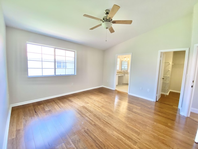 unfurnished bedroom with lofted ceiling, a spacious closet, ceiling fan, ensuite bath, and light hardwood / wood-style flooring